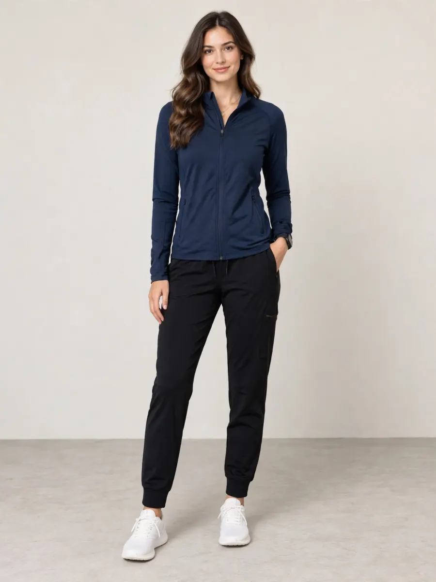 The same woman in a navy zip-up training jacket, black joggers and white sneakers